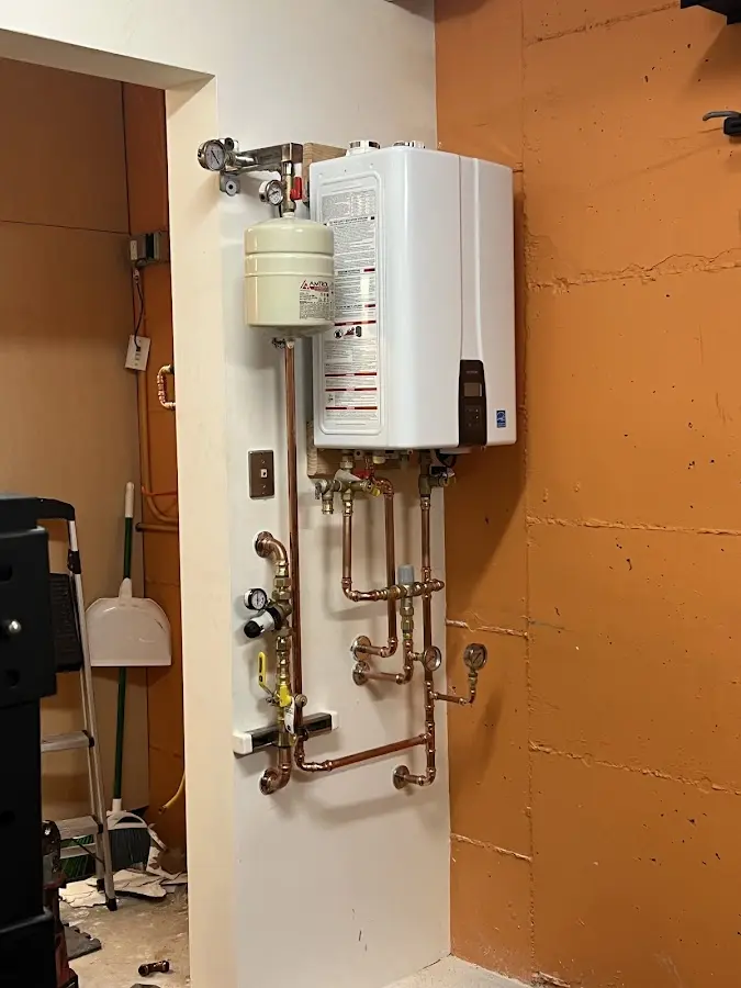 Plumbing technician inspecting water heater connections in Delran